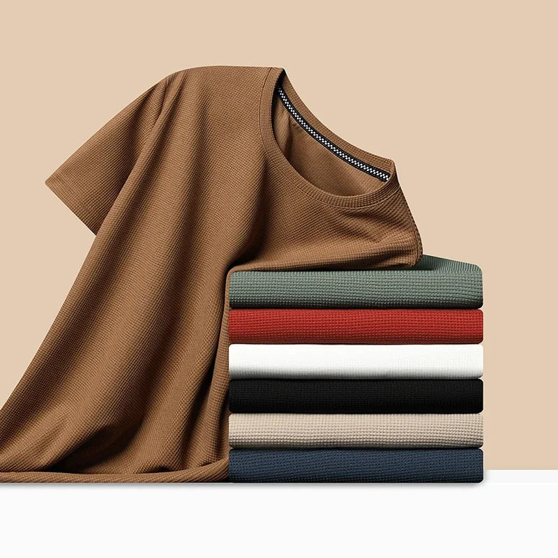Stack of folded shirts in various colors on a beige background