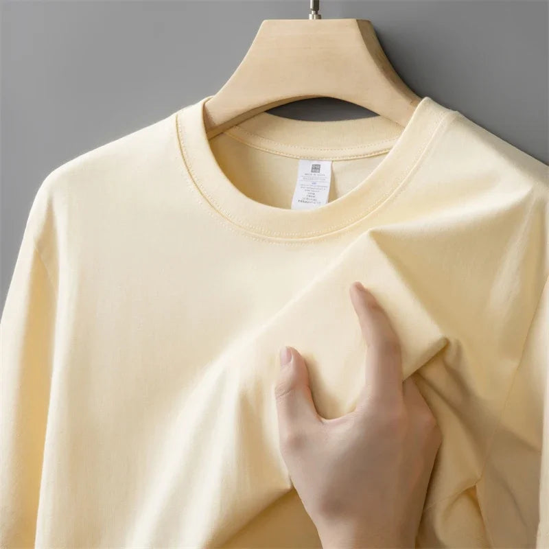 Beige sweatshirt on a hanger with a hand touching it against a gray background