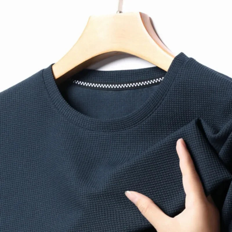 Dark blue textured sweater on a hanger with a hand touching the fabric