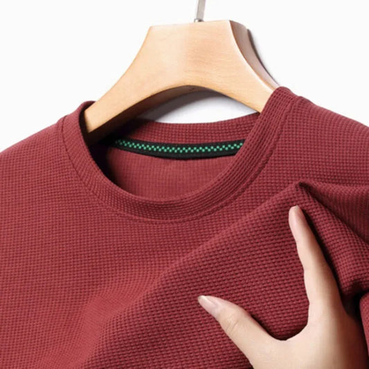 Red textured shirt on a hanger with a hand touching the fabric