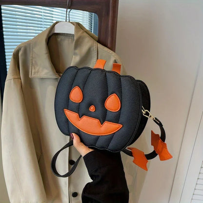 Black pumpkin-shaped bag with orange details held by a person against a beige jacket.