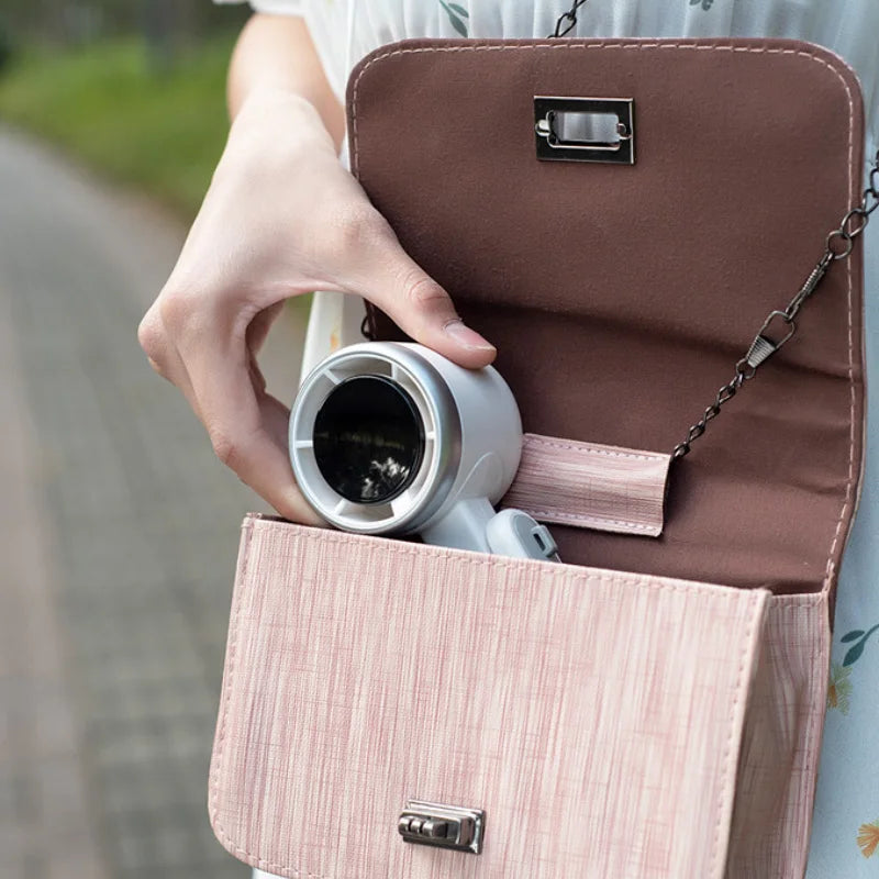 Person holding a brown handbag with a pink interior, containing a white thermos.