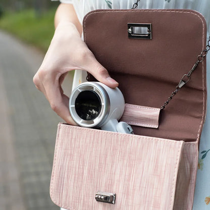 Person holding a brown handbag with a pink interior, containing a white thermos.