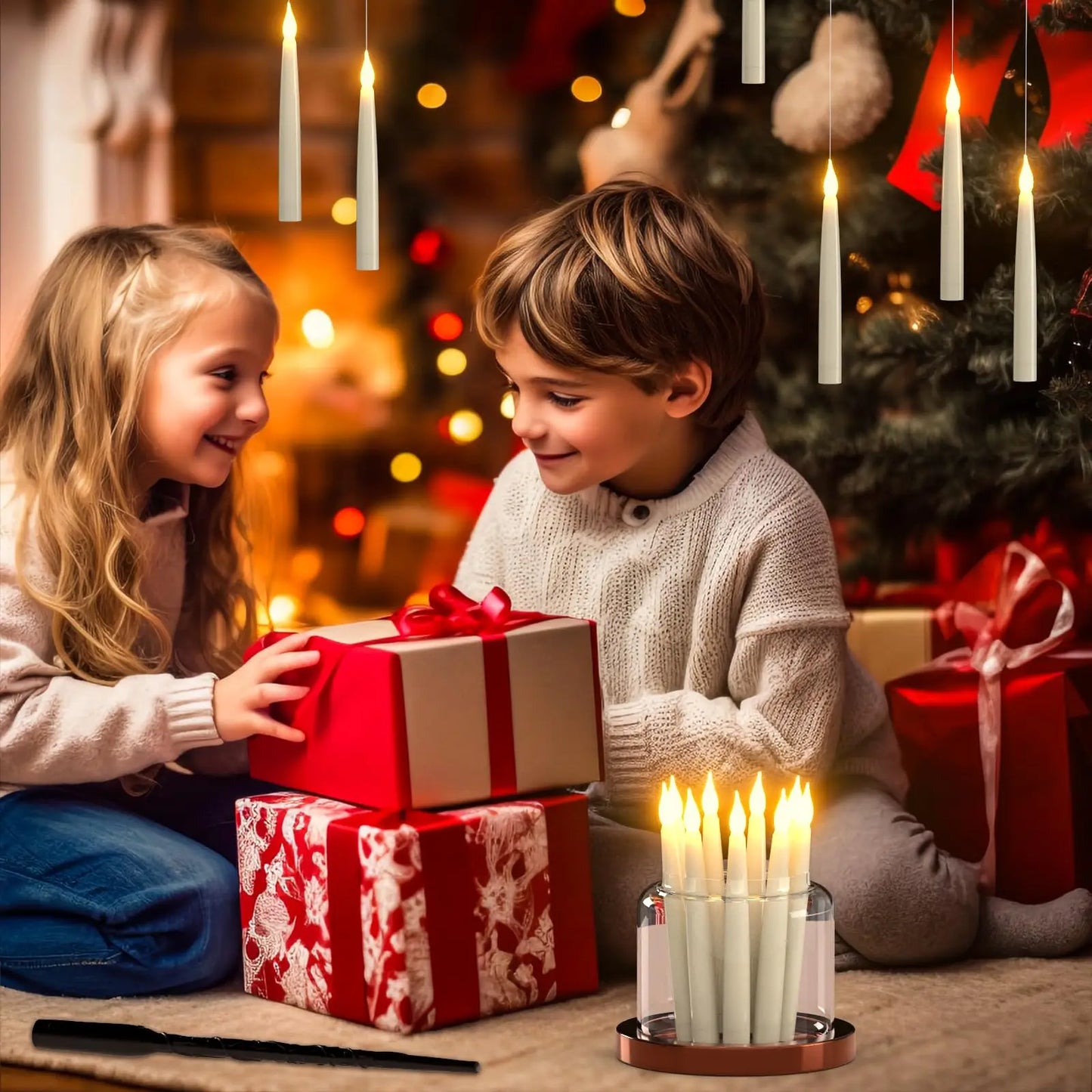 Two children exchanging Christmas presents with a decorated tree and candles in the background.