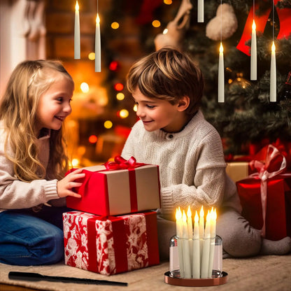 Two children exchanging Christmas presents with a decorated tree and candles in the background.