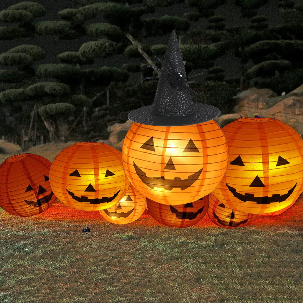 Halloween-themed lanterns with jack-o'-lantern faces and a witch hat on a grassy background.