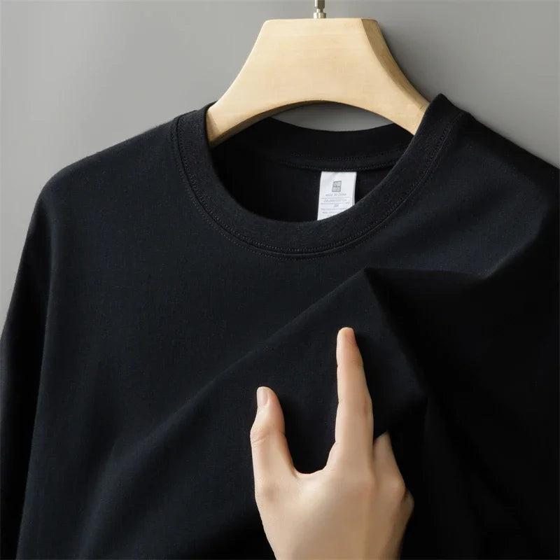 Black sweatshirt on a hanger with a hand touching the fabric against a gray background